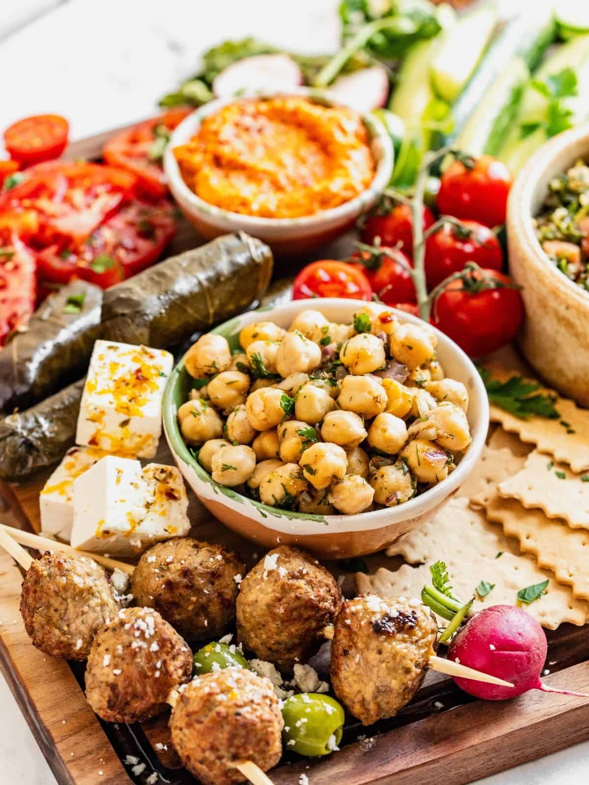 A mezze board with stuffed grape leaves, meatballs and marinated chickpeas.