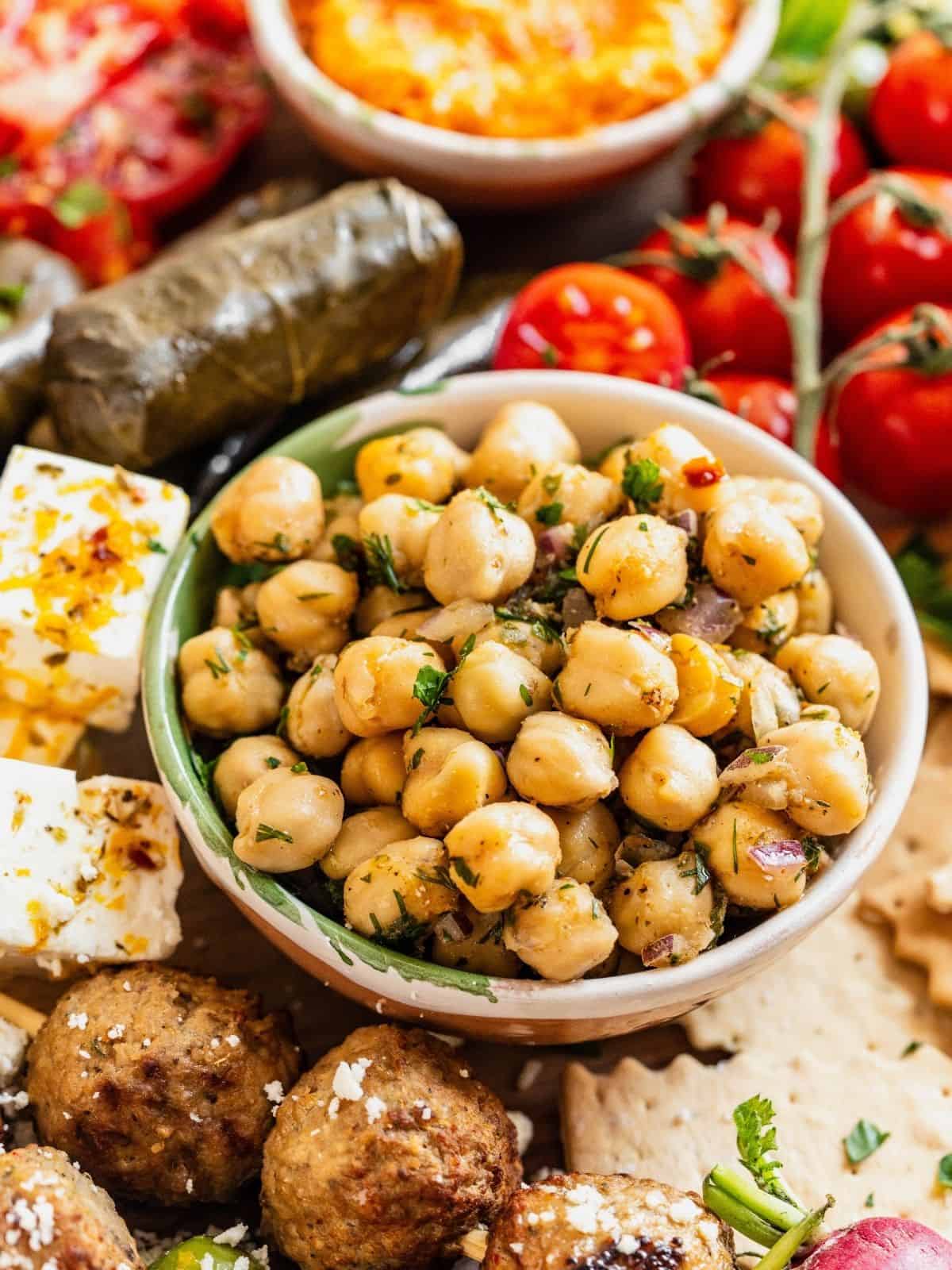 A mezze board with stuffed grape leaves, meatballs and marinated chickpeas.