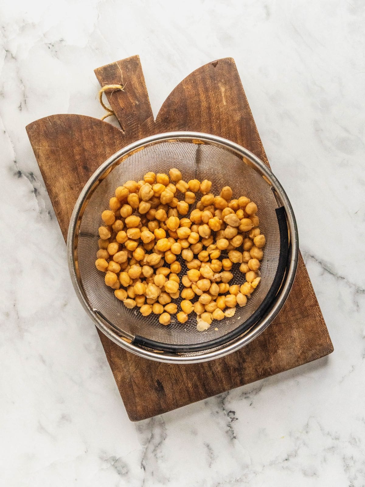 Chickpeas draining in a metal colander.