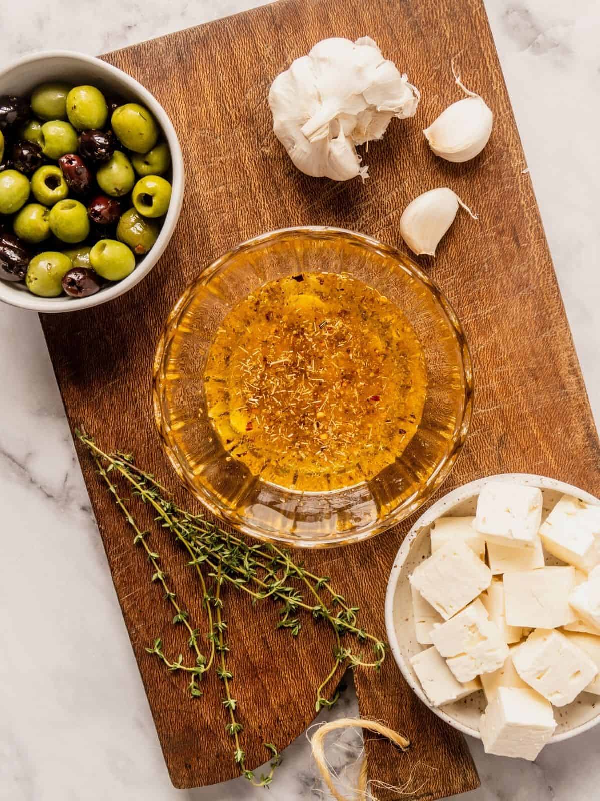 Bowl of marinade with olive oil, garlic, spices and zest on a wooden board.