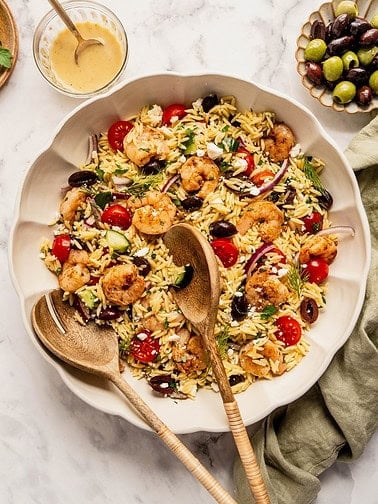 Bowl of orzo salad with grilled shrimp, tomatoes and olives.