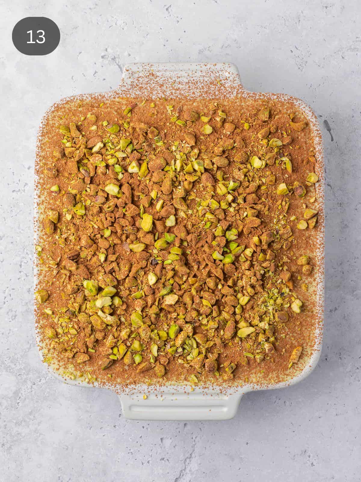 A tray of orange pistachio tiramisu decorated with cocoa and crushed pistachios.