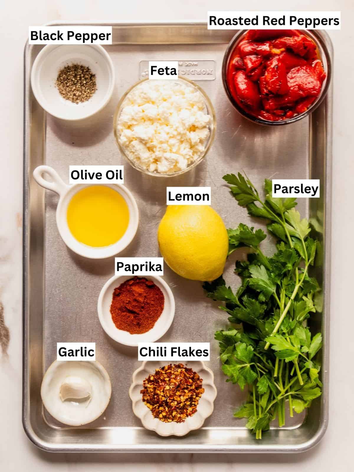 Red pepper feta dip (Greek Tirokafteri or Htipiti) recipe ingredients with individual labels on a metal tray.