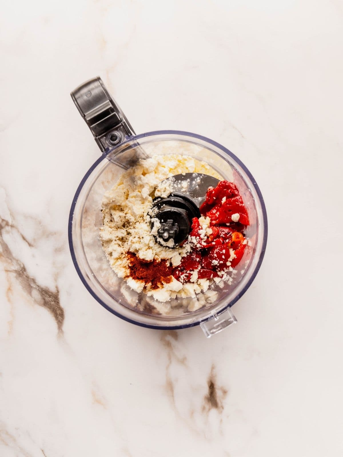 Small food processor with feta, roasted red peppers, garlic, black pepper, olive oil and smoked paprika.