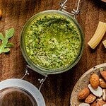 Arugula pesto in a class jar on a wooden tray.