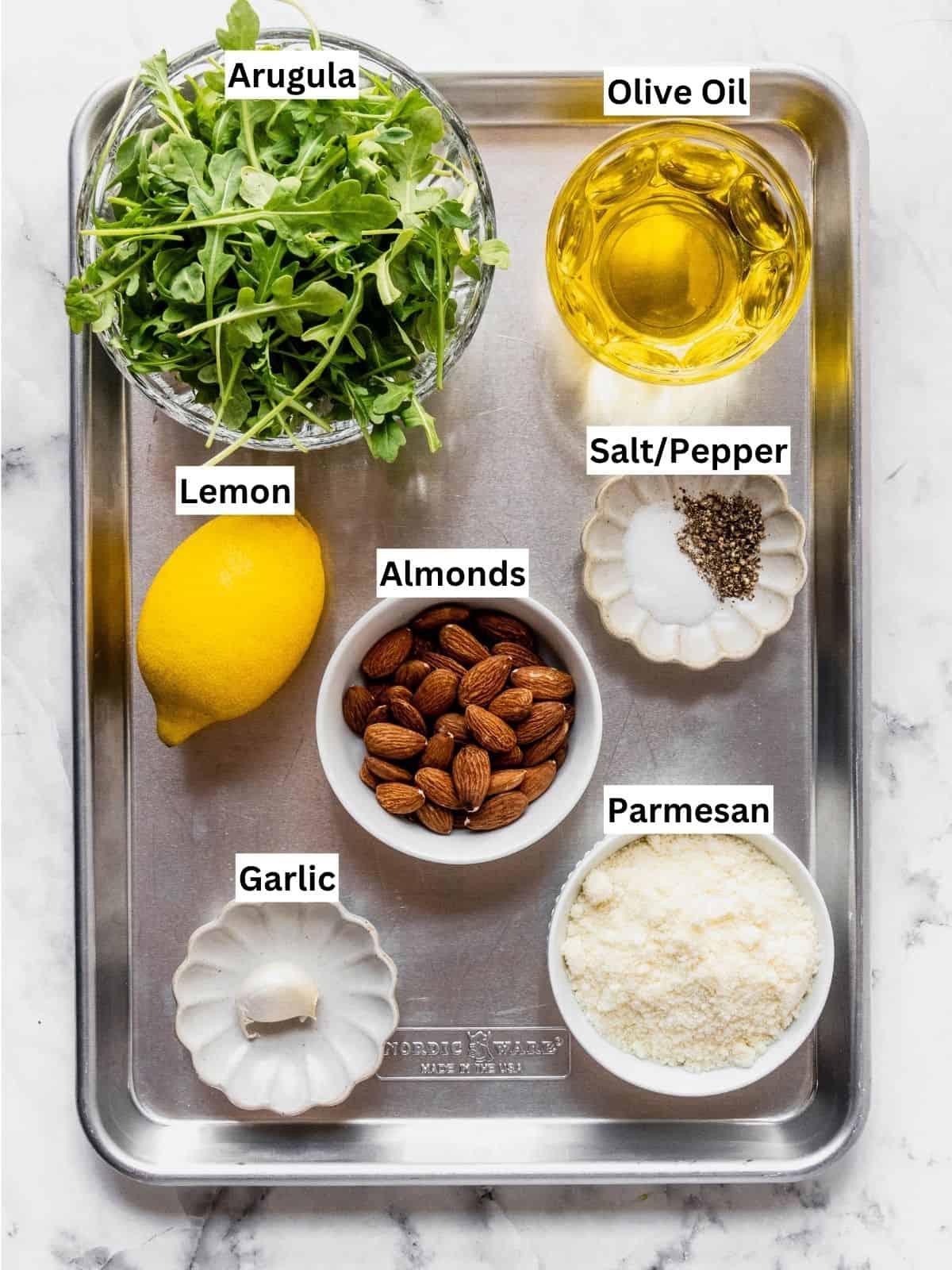 Arugula pesto recipe ingredients with individual labels on a metal tray.