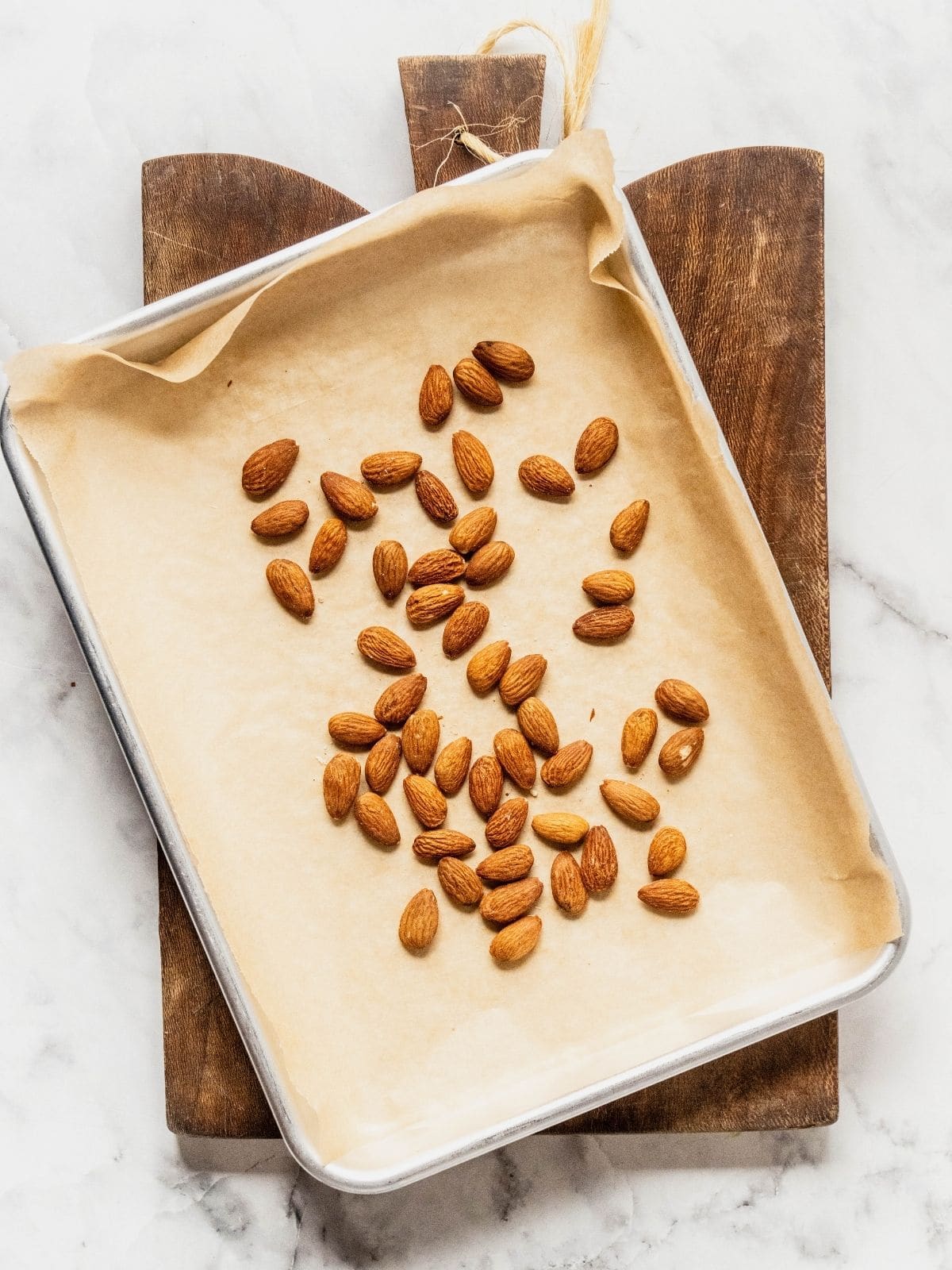 Almonds on a parchment paper lined baking sheet.