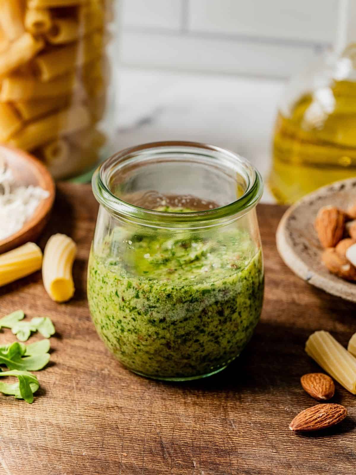 Arugula pesto in a class jar on a wooden tray.
