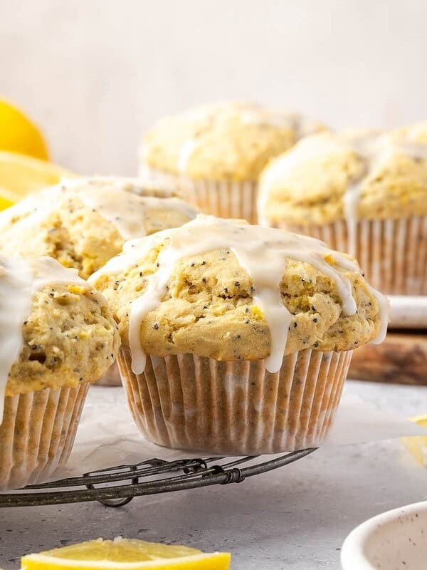 Lemon poppy seed muffins with lemon icing on a cooling rack.