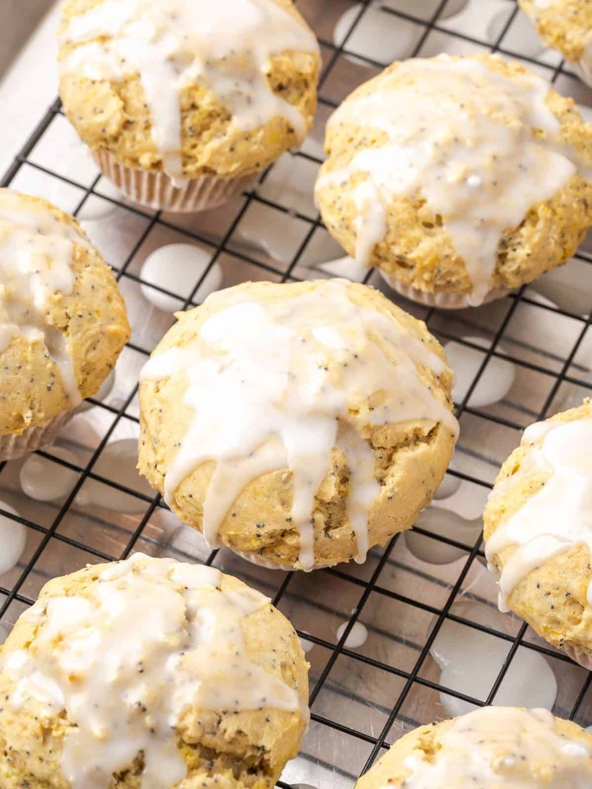Lemon poppy seed muffins with lemon icing on a cooling rack.