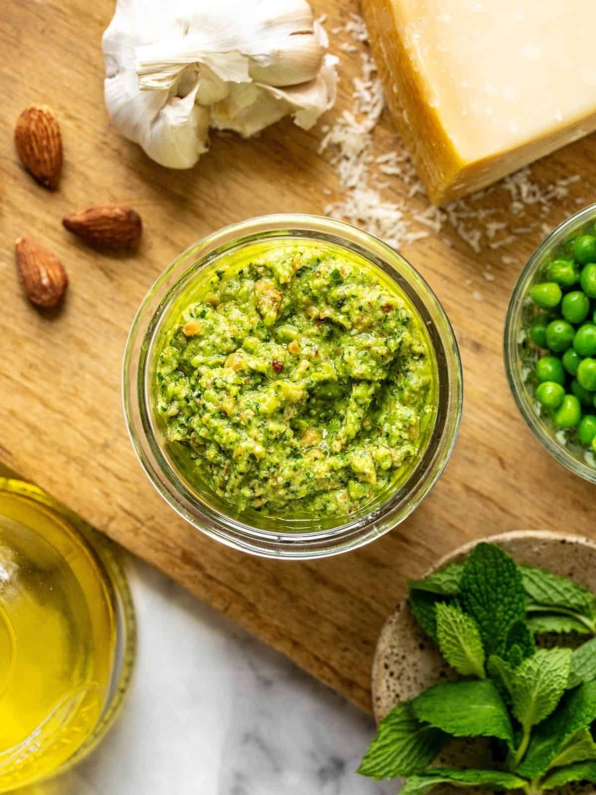 Pea and mint pesto in a mason jar on a wooden board.