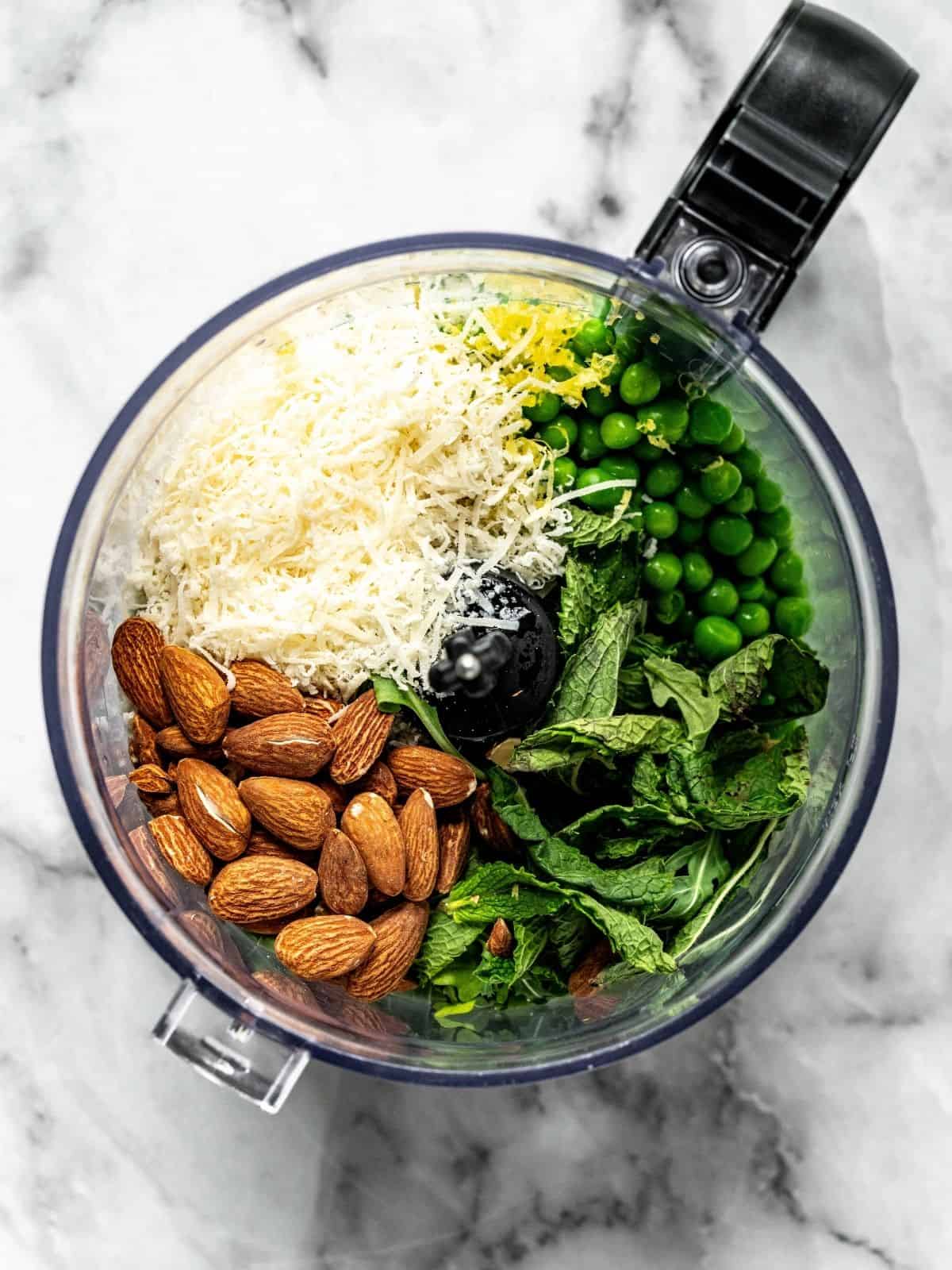 Food processor with peas, mint, almonds, parmesan, lemon zest and juice.