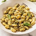 Gnocchi tossed with pistachio pesto and garnished with fresh basil in a bowl.