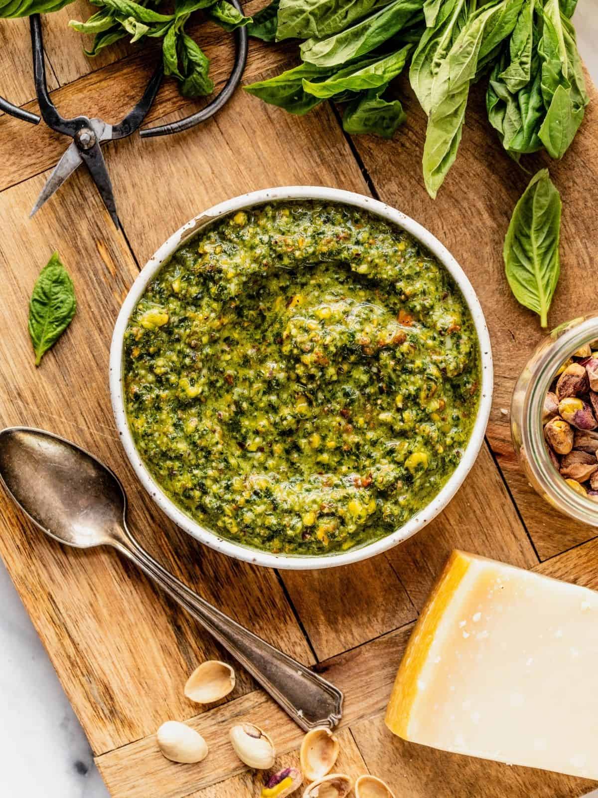 Pistachio pesto in a bowl set on top of a wooden board.