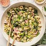 Bowl of spring pasta salad loaded with asparagus, radish, spinach, herbs and a tangy sumac honey dressing.