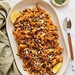 Platter of braised cabbage with white beans garnished with feta, parsley and lemon.