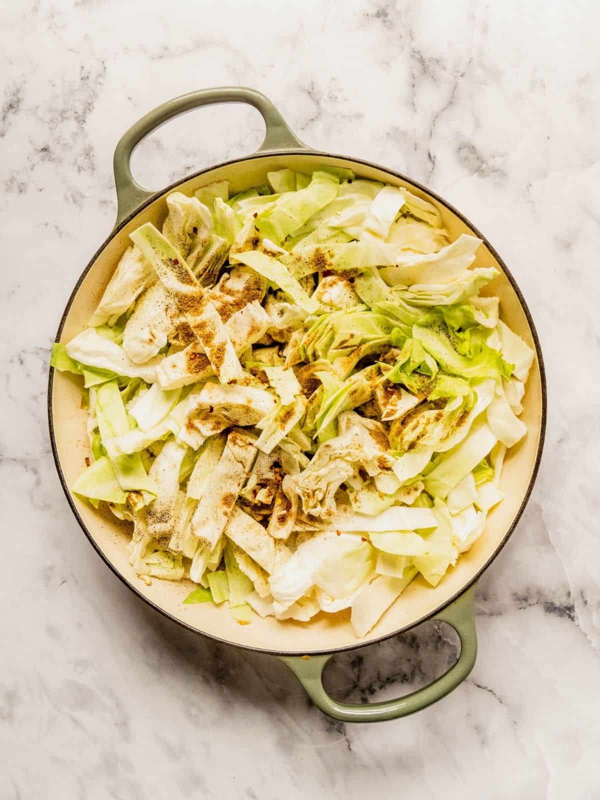 Adding the chopped cabbage and cumin to the pot.