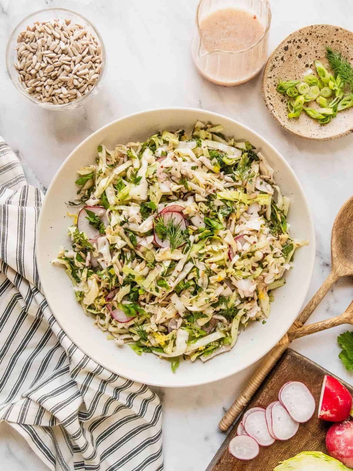 No mayo coleslaw with radish, fresh herbs in a lemon sumac dressing in a bowl.