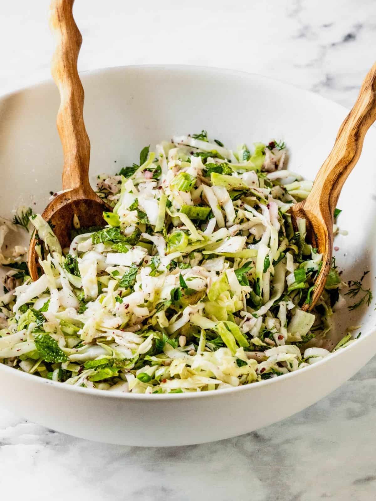 No mayo coleslaw with radish, fresh herbs in a lemon sumac dressing in a bowl.