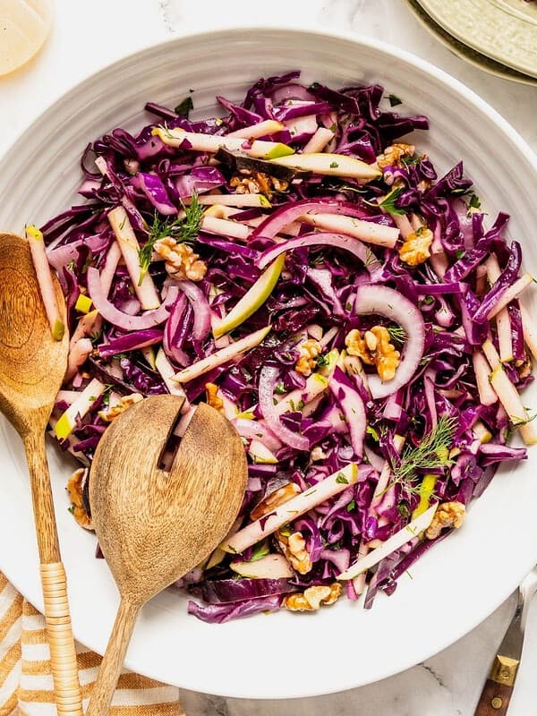 Purple cabbage slaw with apples and walnuts in a bowl.