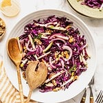 Purple cabbage slaw with apples and walnuts in a bowl.