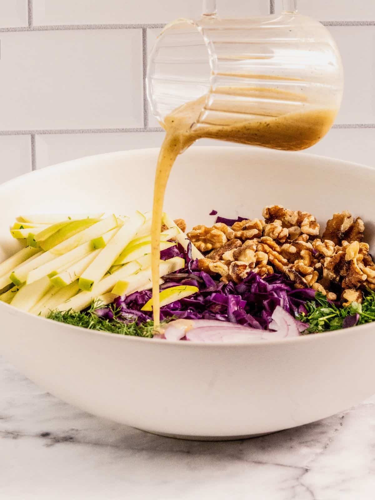 Pouring dressing over the salad ingredients.