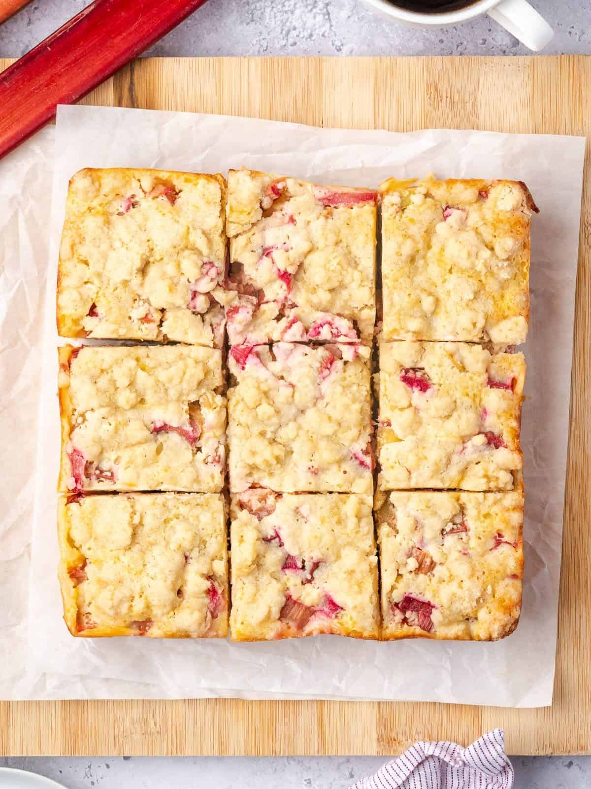 The rhubarb custard bake sliced into 9 squares on a wooden tray.