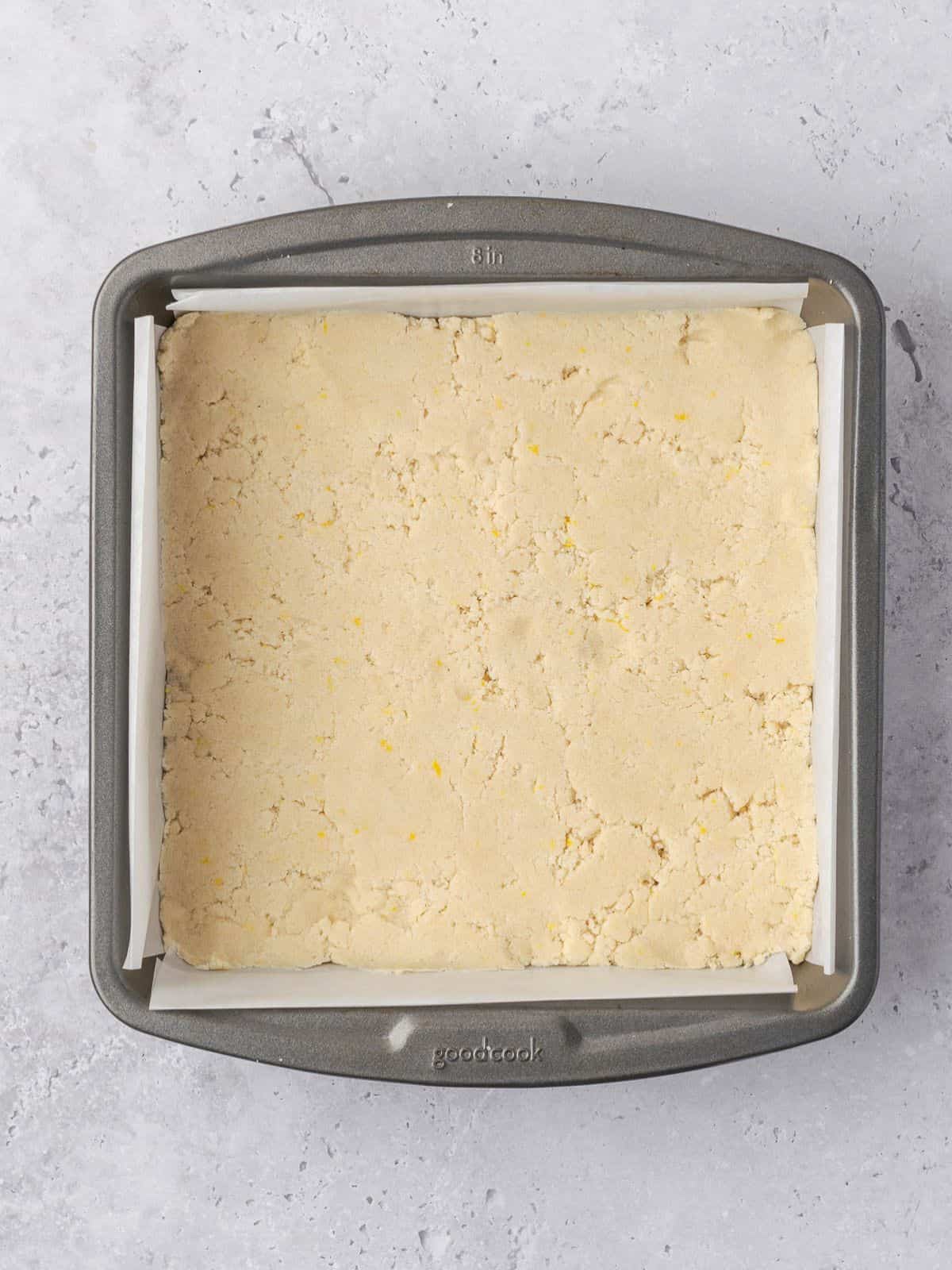 The crust pressed down firmly in the bottom of the metal baking tray before baking.