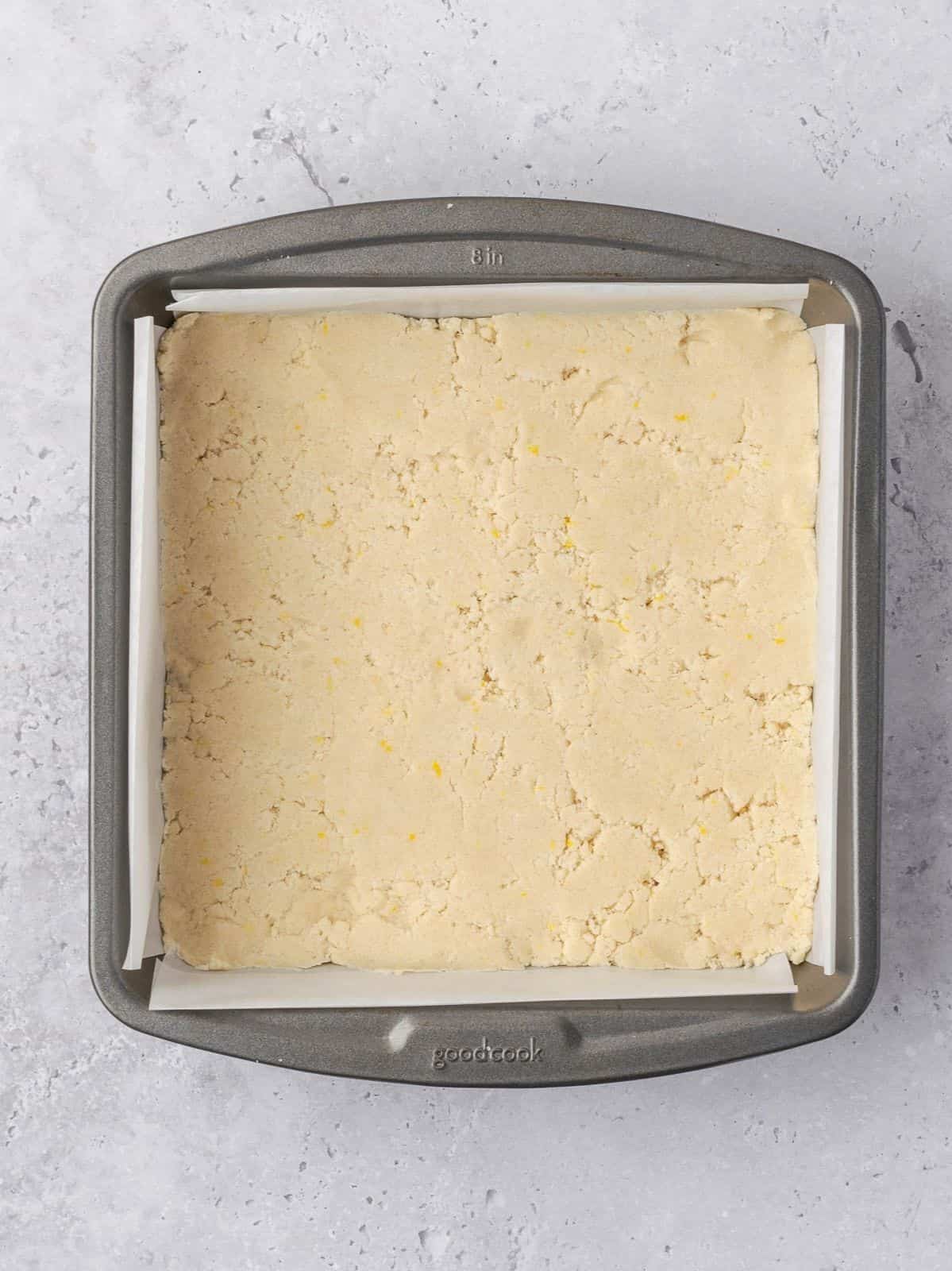 The crust pressed down firmly in the bottom of the metal baking tray before baking.