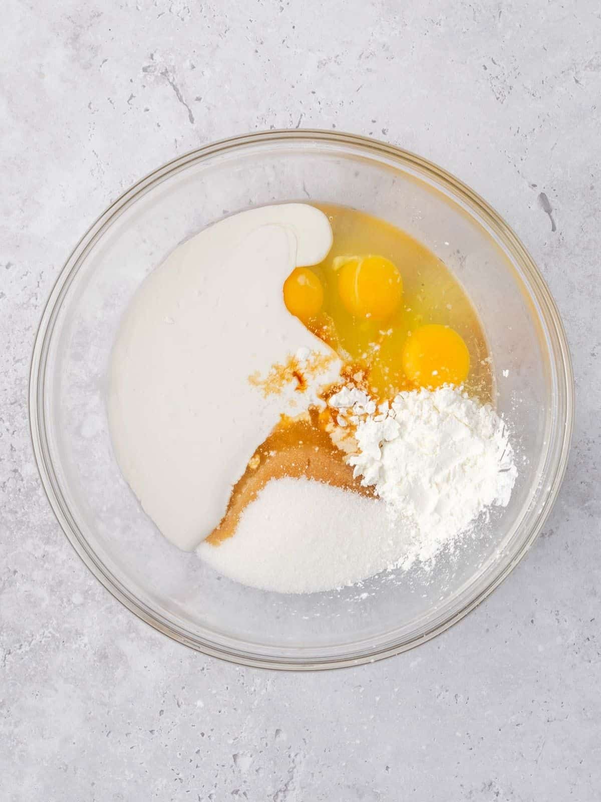 Bowl with eggs, cream, corn starch and vanilla extract.
