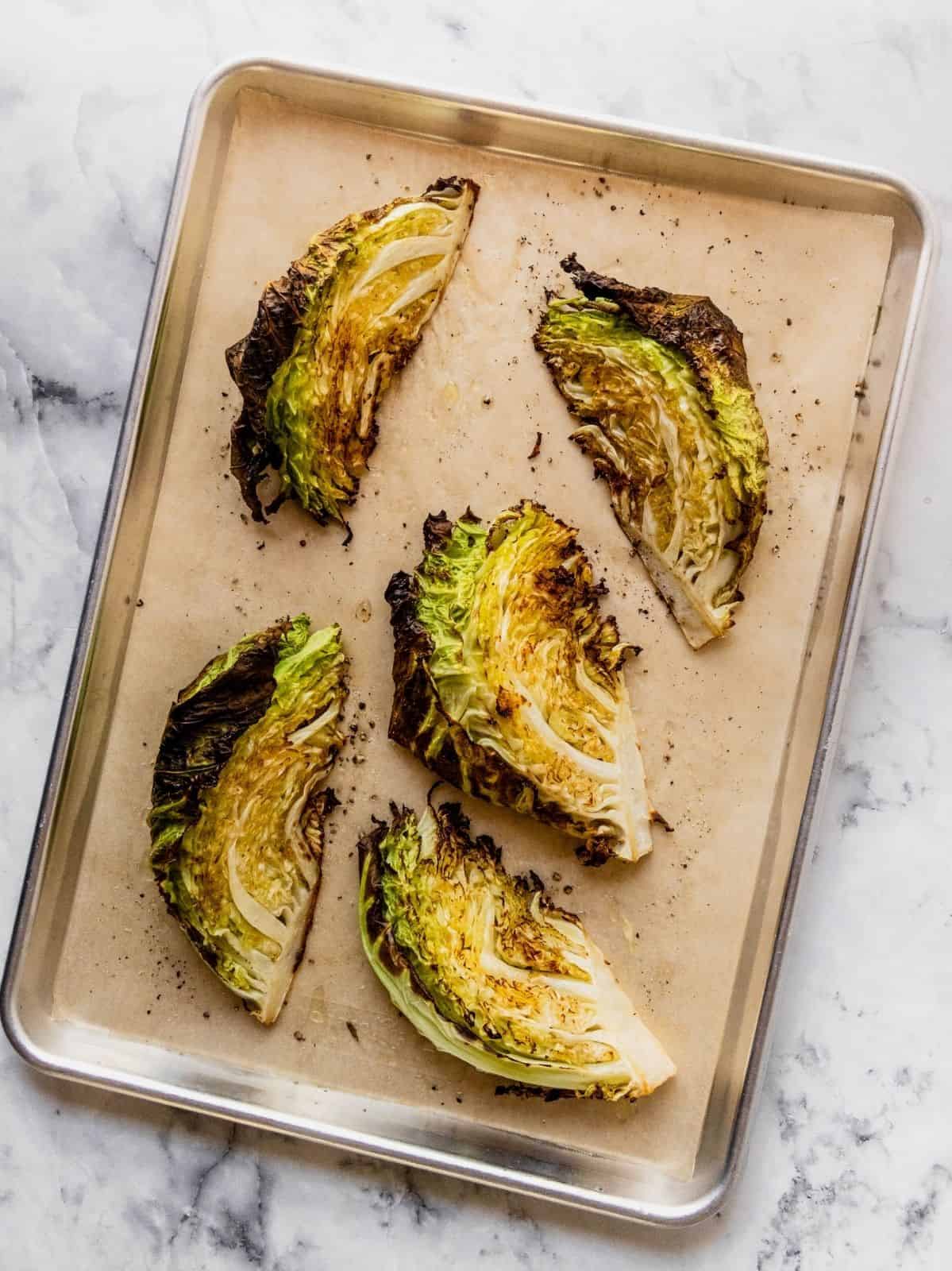 Roasted cabbage wedges on a parchment paper lined baking tray.