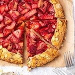 Sliced strawberry rhubarb galette with almond crust on parchment paper.