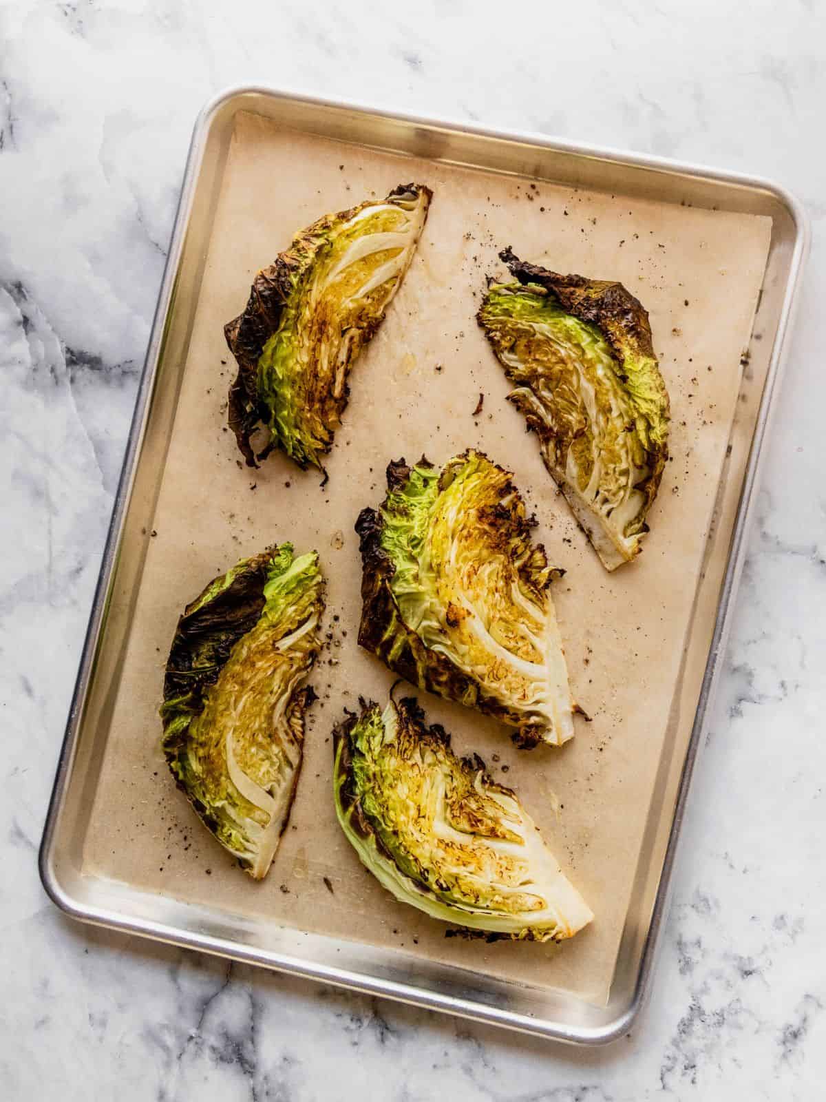 Roasted cabbage wedges on a parchment paper lined baking tray.