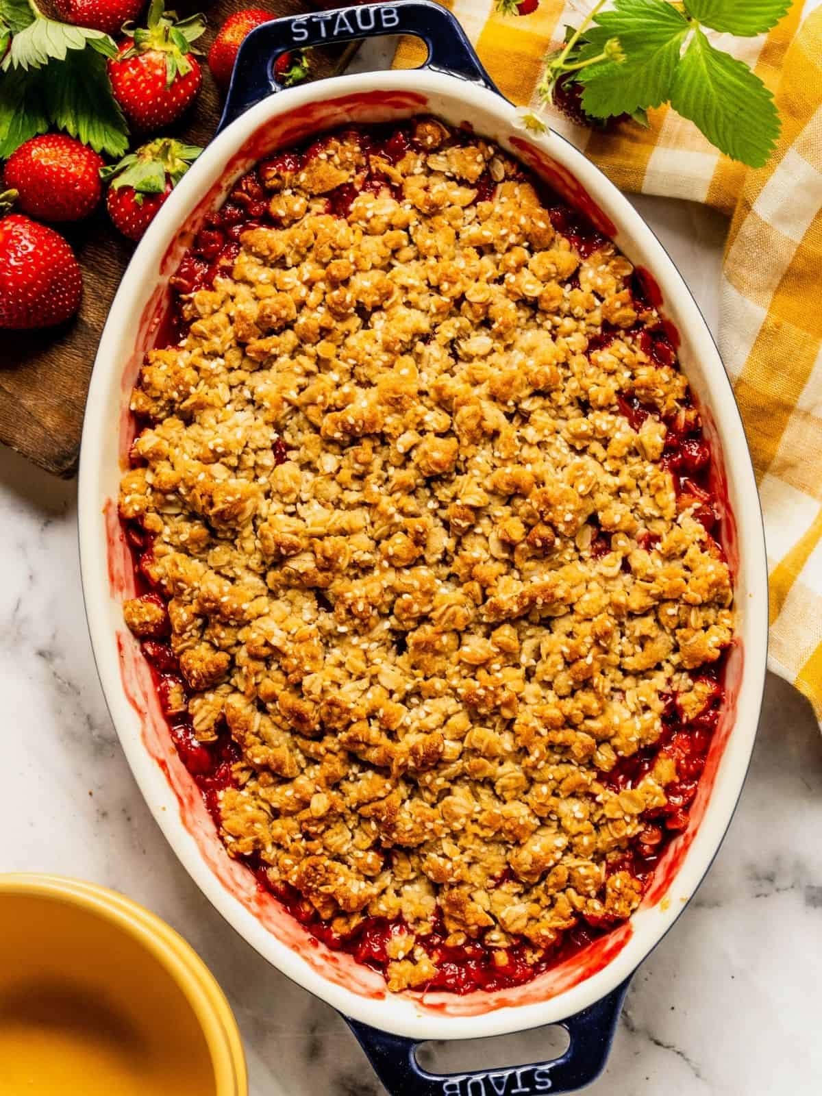 Baked and bubbling strawberry rhubarb crisp in an oval baking dish.