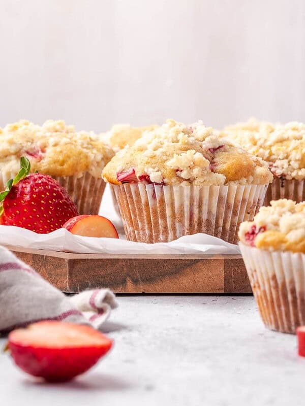 Strawberry rhubarb muffins with lemon streusel topping on a wooden board.