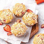 Strawberry rhubarb muffins with lemon streusel topping on a wooden board.