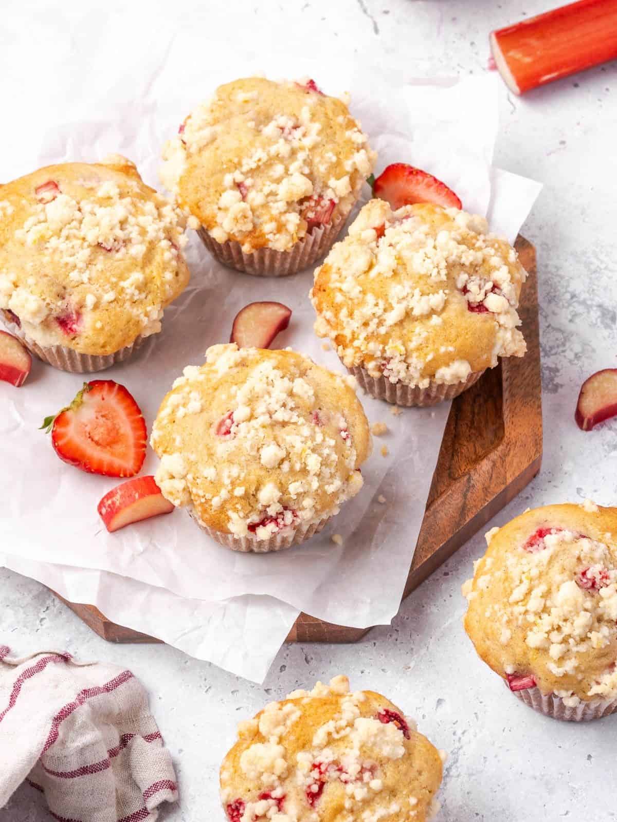 Strawberry rhubarb muffins with lemon streusel topping on a wooden board.