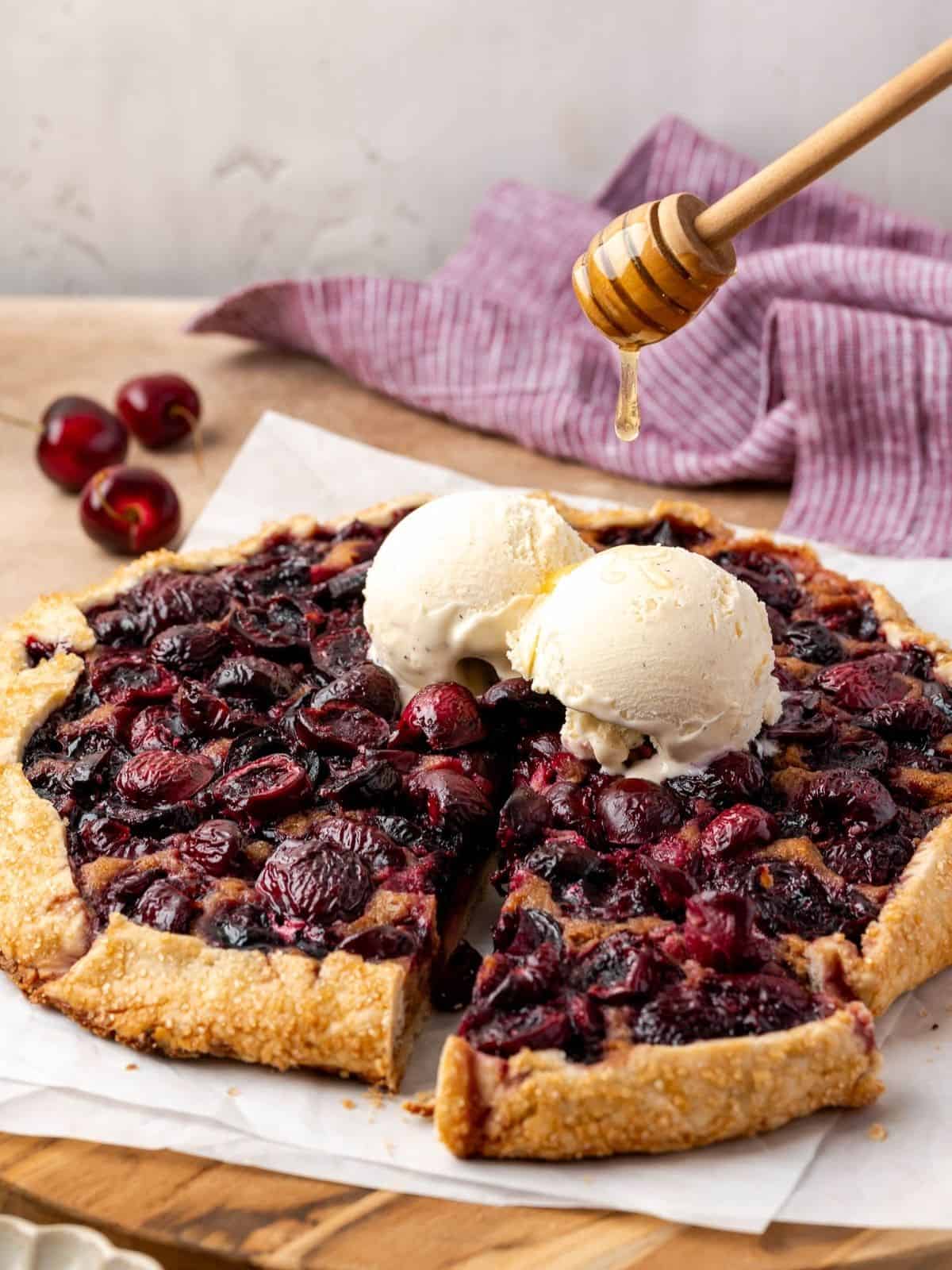 Cherry galette with walnut frangipane topped with two scoops of vanilla ice cream and honey drizzle.