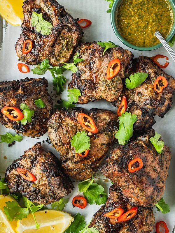 North African grilled lamb loin chops garnished with coriander and chili with a side of chermoula sauce.