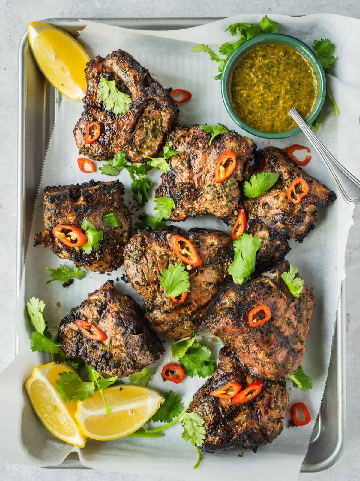 North African grilled lamb loin chops garnished with coriander and chili with a side of chermoula sauce.
