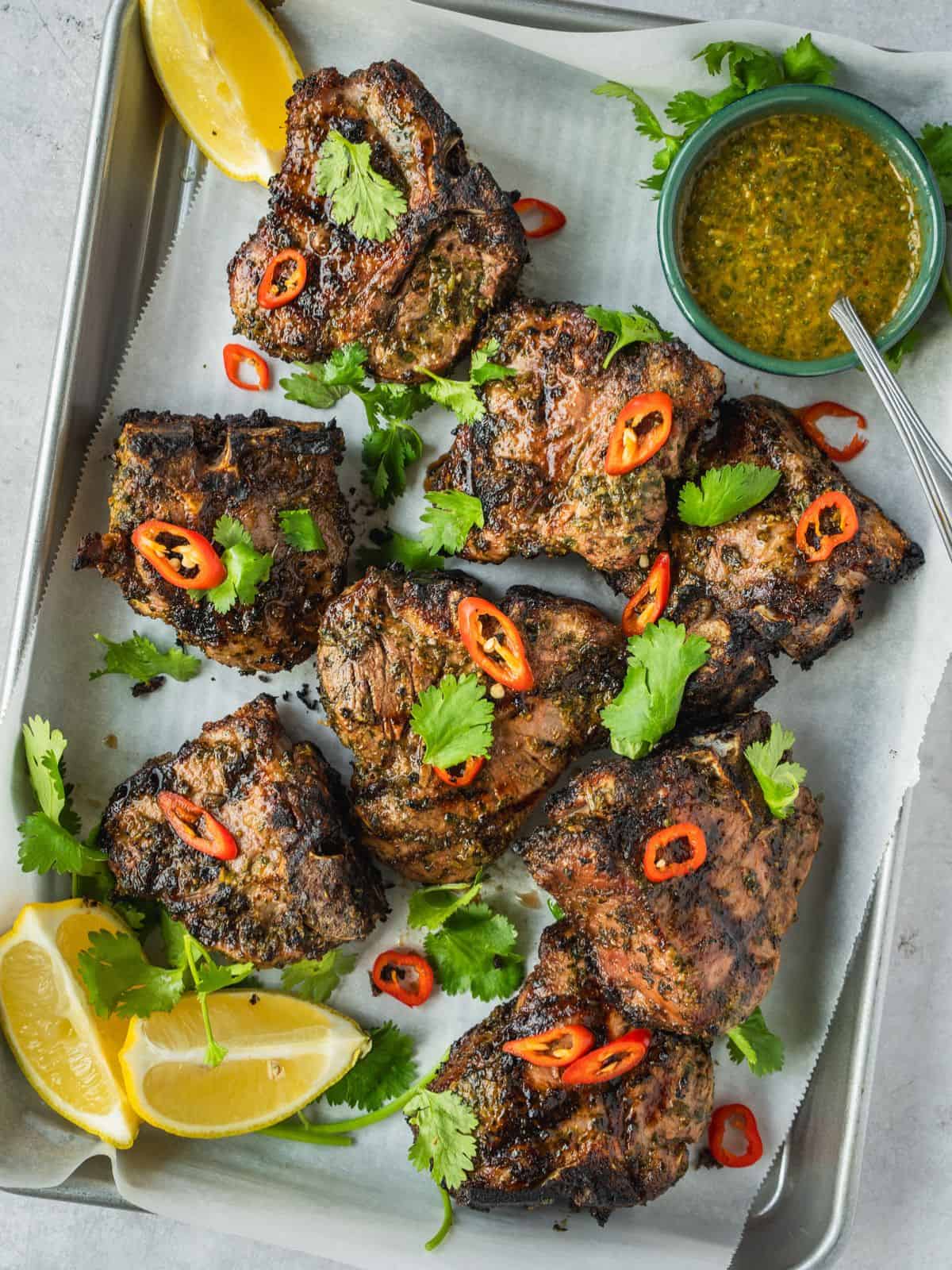 North African grilled lamb loin chops garnished with coriander and chili with a side of chermoula sauce.