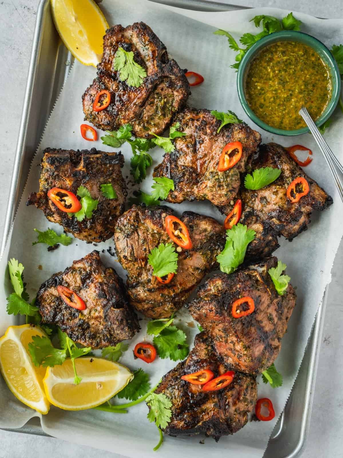 North African grilled lamb loin chops garnished with coriander and chili with a side of chermoula sauce.