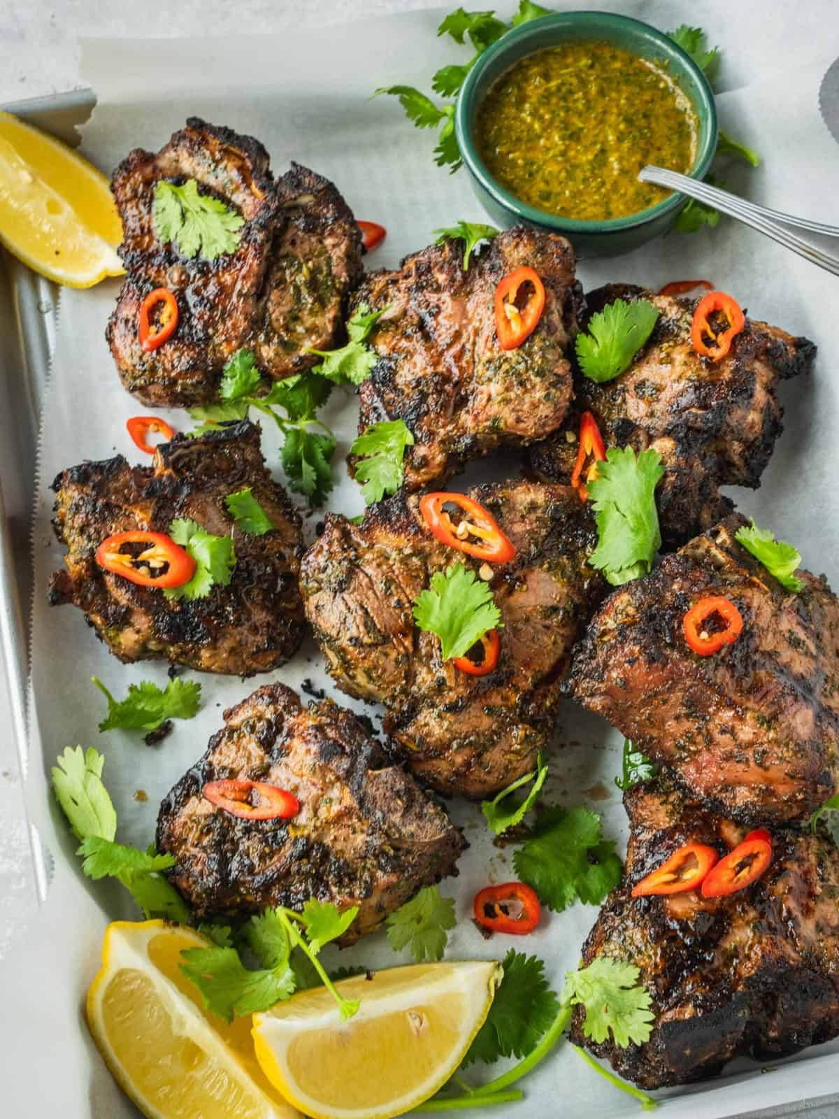 North African grilled lamb loin chops garnished with coriander and chili with a side of chermoula sauce.