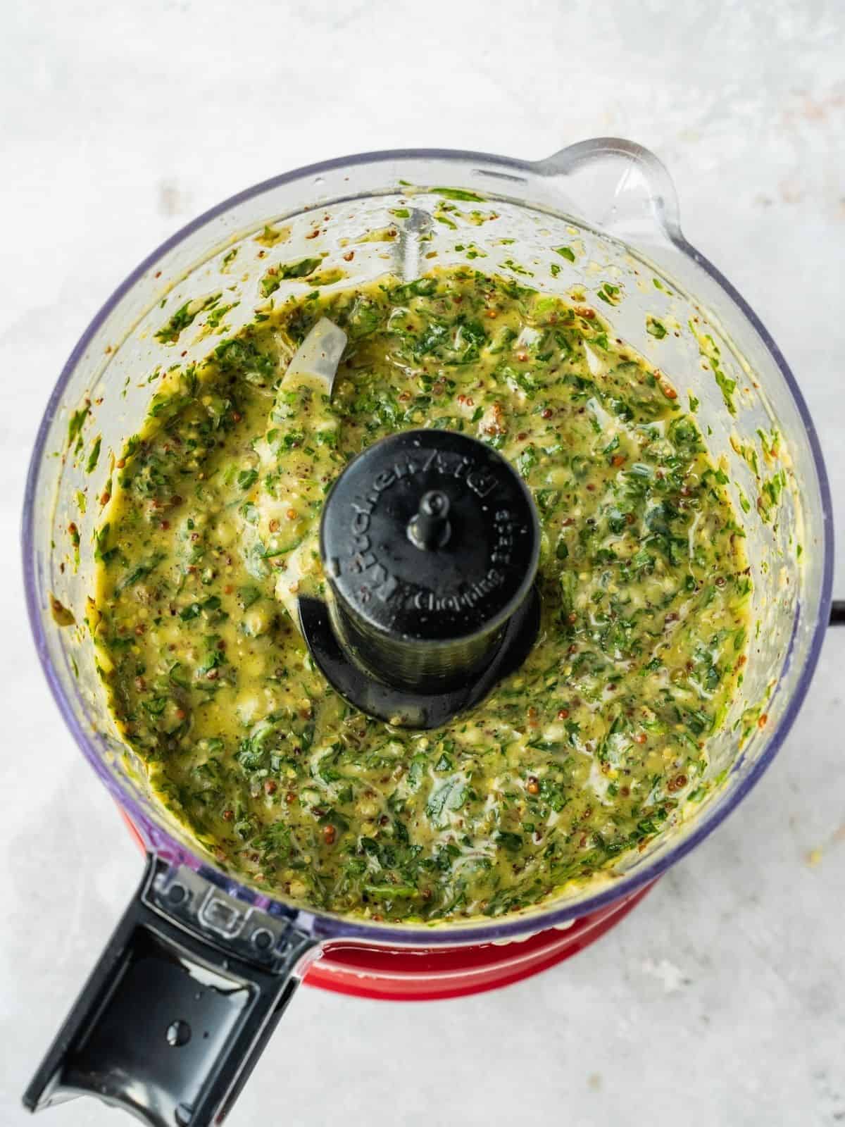 The pomegranate molasses sumac herb sauce getting prepared in a food processor.