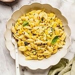 Bowl of creamy corn and zucchini pasta garnished with basil, lemon zest, chili flakes and parmesan.