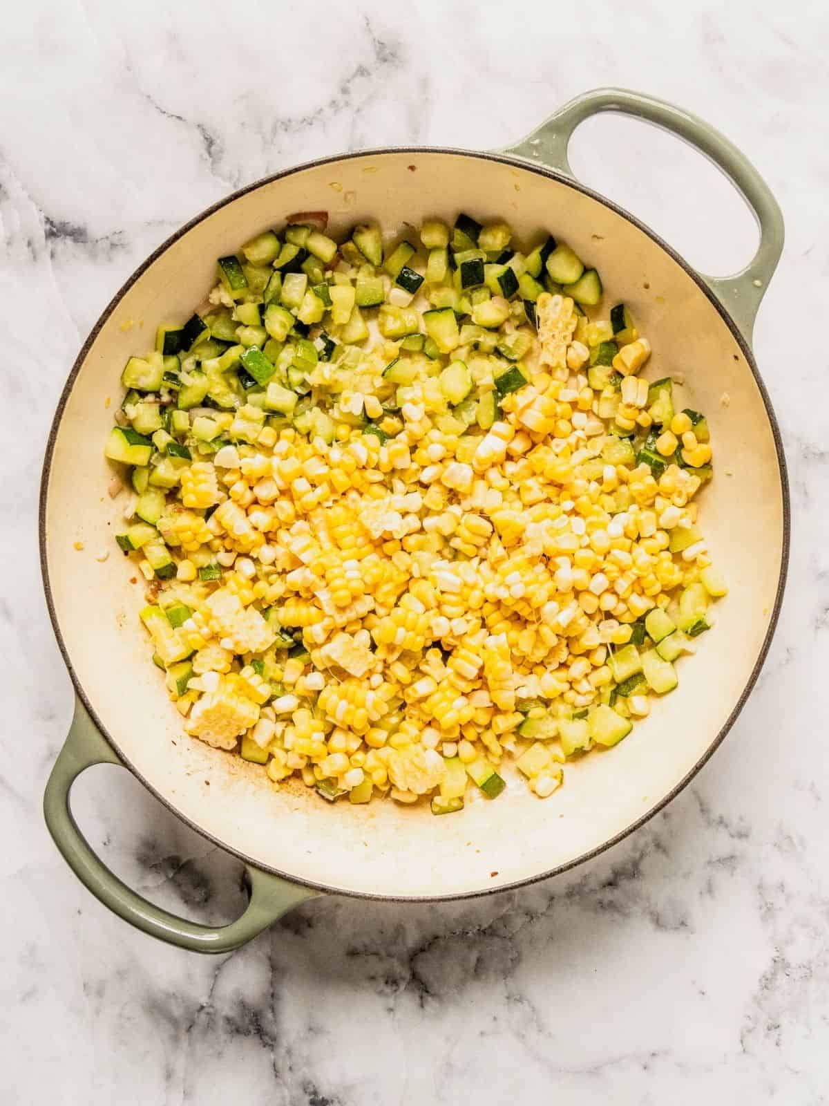 Corn getting added to the fried zucchini.