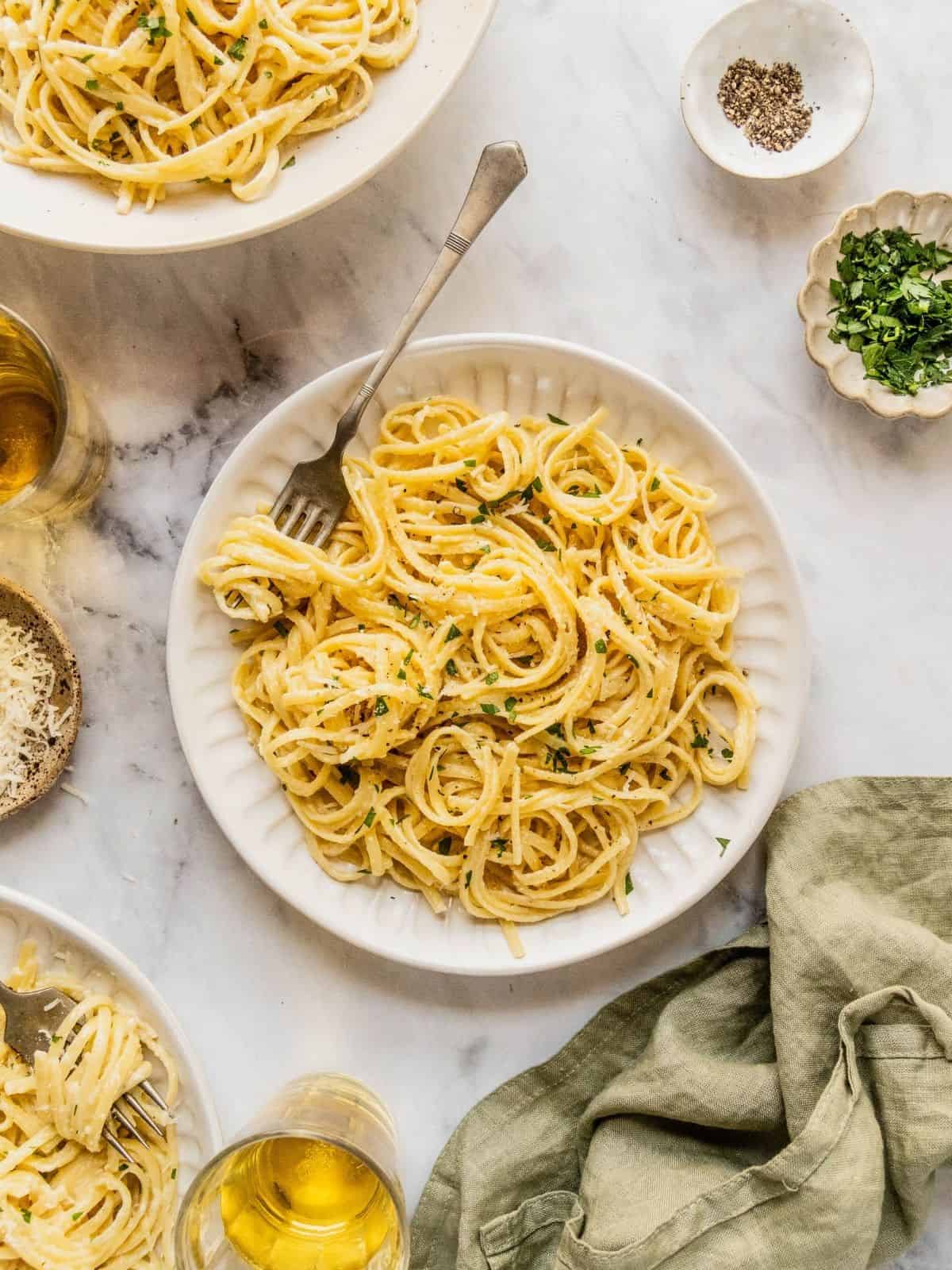 Bowl of creamy pasta al limone garnished with herbs and Parmesan.