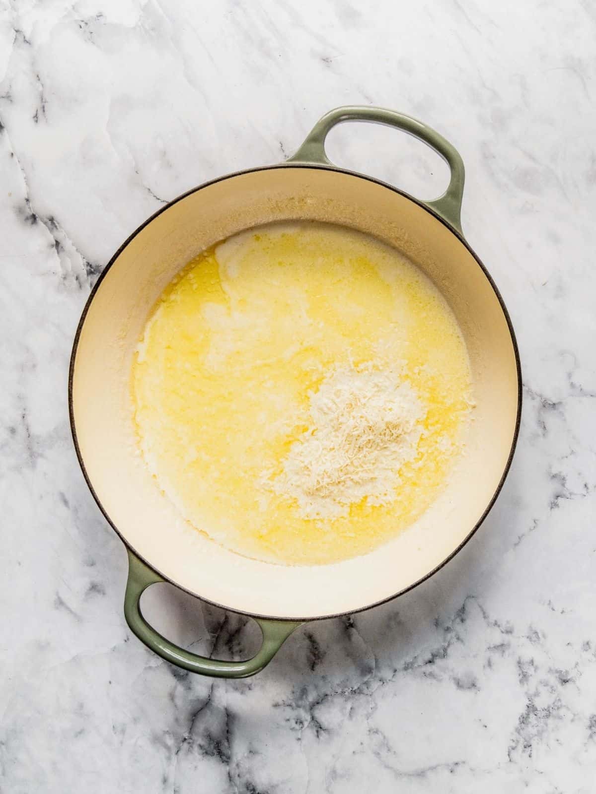 Parmesan being added to the creamy base.