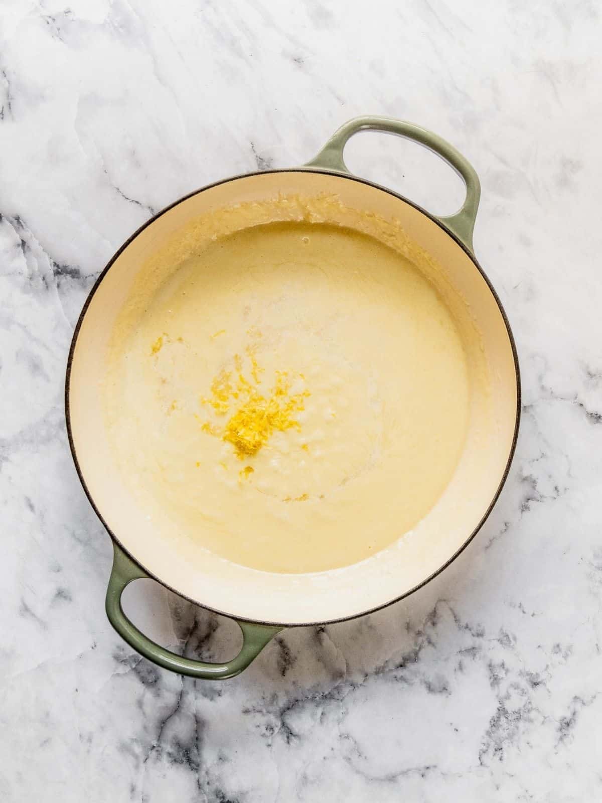Lemon and lemon zest being added to the sauce in a pot.