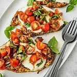Platter with grilled chicken margherita garnished with cherry tomatoes and basil.